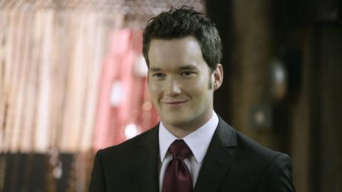 A man with dark hair and a red tie