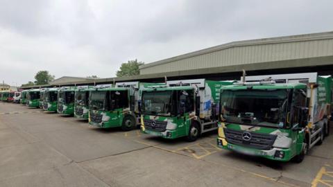 A row of bin lorries in a depot