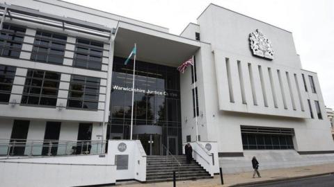 A google street view image of the outside of a court. a large white building with glass frontage and bars on the windows