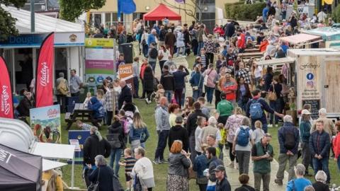 Crowds in a field with food vendors scattered around 