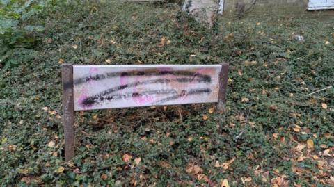 A rusty, faded street sign covered in graffiti.