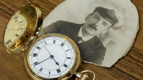 A gold pocket watch with a black and white photo of a man. 