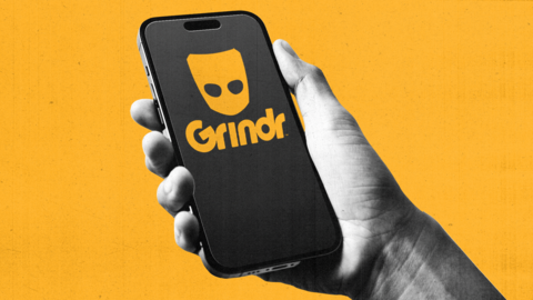 A hand holds a mobile phone with Grindr logo on it. Background is bright yellow. 