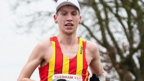 A runner is wearing a vest with vertical red and yellow stripes. 