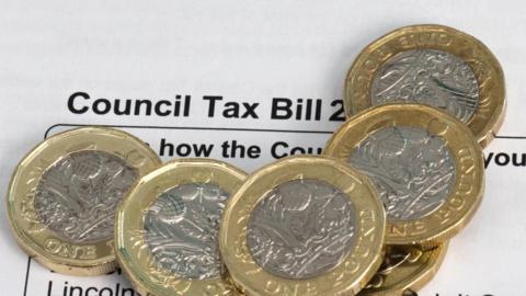 Some pound coins piled on top of a council tax bill.