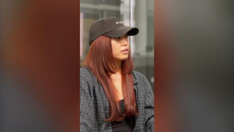 Jennifer An wearing a black baseball cap and a checkered shirt.