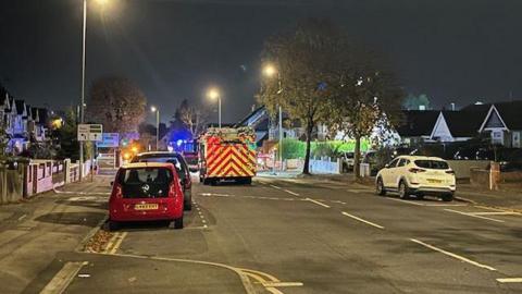 A fire engine driving down the middle of a road at night