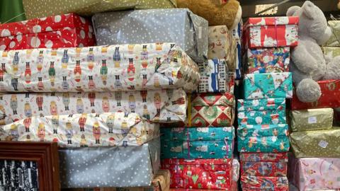 Piled up shoeboxes wrapped in Christmas paper.