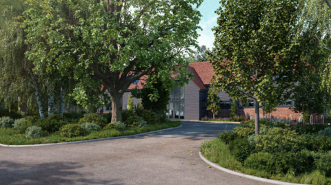 A proposed building set among mature trees and landscaped planting, viewed from a curved access road. The timber-clad building with a red-tiled pitched roof is partially screened by greenery, with a glazed entrance at the centre.