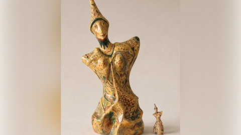 A large sculpture of a person with no arms and legs, wearing a hat and with a smile on their face. It has been decorated with a unique pattern. A miniature version has been placed next to it.