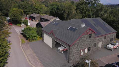 A CGI image of what the proposed mountain rescue base would look like. It is part one storey and part two storeys high, with slate cladding and garages for MRT vehicles.