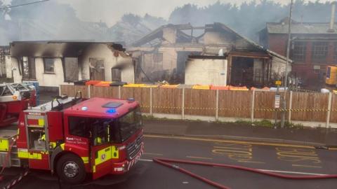 A burnt out building with a fire engine in front of it