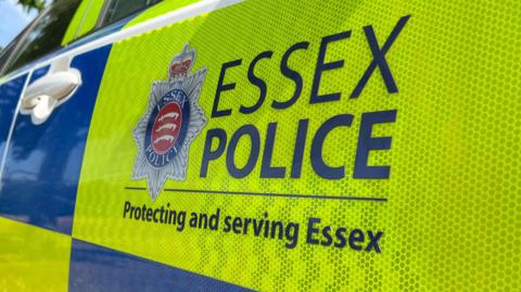 Left side of a police car with blue and yellow logo and writing saying Police - Protecting and serving Essex.