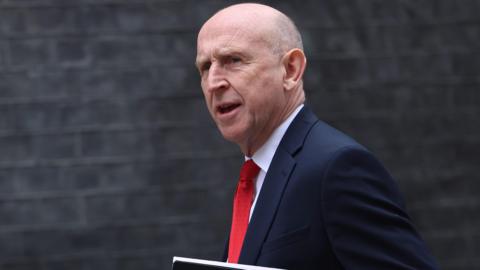 Secretary of State for Defence John Healey arrives for a cabinet meeting wearing a dark suit and red tie