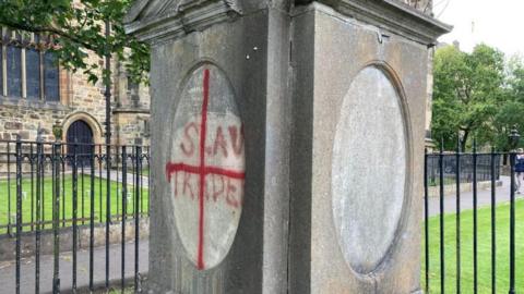 Gravestone in Lancaster Priory vandalised with the words slave trader and a red cross. 