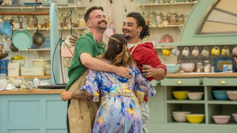 Great British Bake Off contestants hugging. 