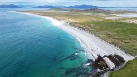 An aerial view of West Beach at Bays of Harris in the Western Isles. There is a long strip of white sand and turquoise sea.
