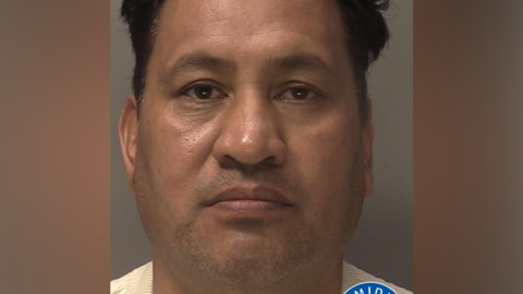 A police mugshot of a man with dark hair. He is wearing a cream jumper. There is a West Midlands Police logo in the bottom right corner.