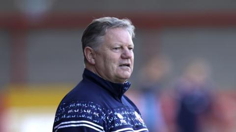 A man wearing a blue tracksuit with white detailing on it.
