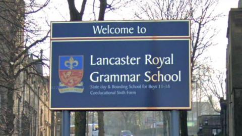 A blue sign on a street in Lancaster saying 'Welcome to Lancaster Royal Grammar School'