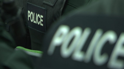 A close-up of the back of police officers' black jackets with police in white letters 