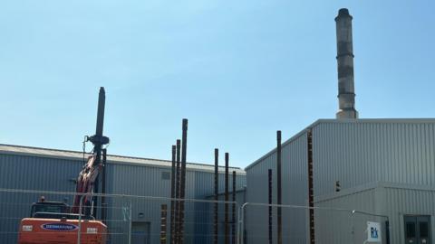 Grey incinerator building with work beside it at Longue Hougue in Guernsey.