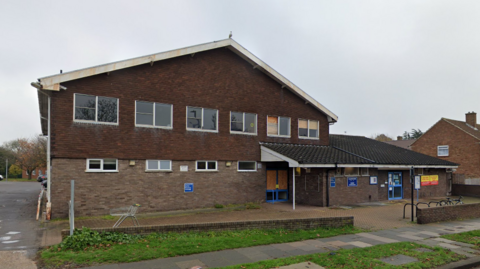 A large double-storey building with six windows across the top floor, and porch above the front door.