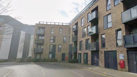 A block of flats. It is made of brown bricks with black windows.