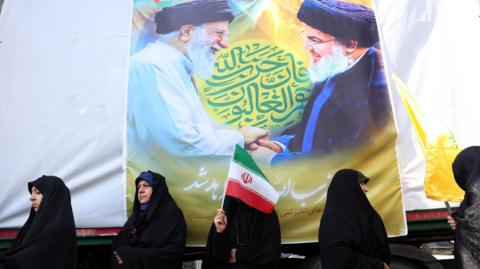 Iranian women stand in front of a poster of Iranian Supreme Leader Ayatollah Ali Khamenei (L) and the late Hezbollah leader Hassan Nasrallah (R) during an anti-Israel rally in Tehran, Iran (27 September 2024)