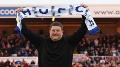 Hartlepool owner Landon Smith lifts a scarf above his head on the pitch ahead of the match against Altrincham.
