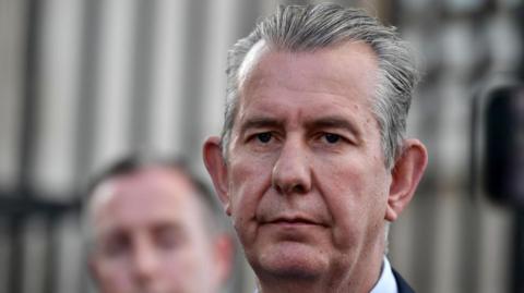 A man, Edwin Poots has grey hair, looking at the camera. 