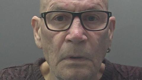 David Newton: The face of convicted murderer David Newton. He is clean shaven and wearing dark-rimmed glasses, a gold earring in his left ear and a brown woollen, round-necked jumper