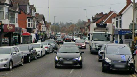 Street view of Evington Road with cars parked on either side of the road