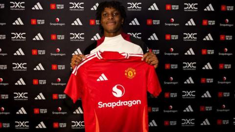 Patrick Dorgu holding up a Manchester United shirt