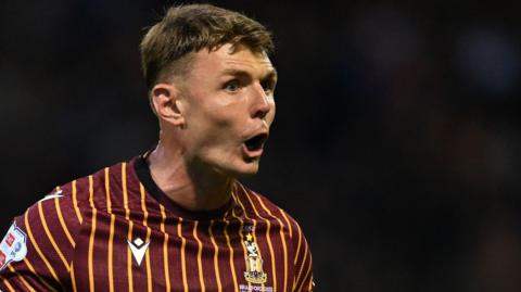 Max Power, while playing for Bradford City, with his hands out wide asking his team-mates for calm.