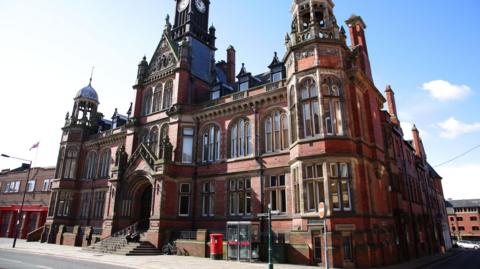 The exterior of York Magistrates' Court - a red brick building with several windows - on a sunny day.