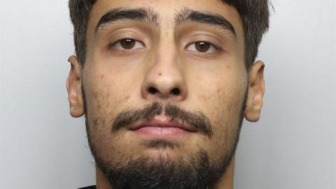 A custody photo of a man with brown eyes, short brown hair and facial hair