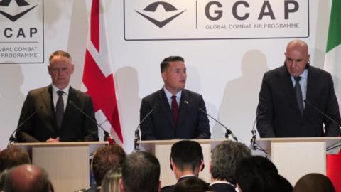 Wes Streeting (centre) speaks at a podium
