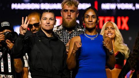 Katie Taylor holds up three fingers as she and Amanda Serrano pose for pictures at a news conference