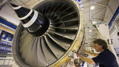 A factory worker helping to construct an aircraft jet engine. 