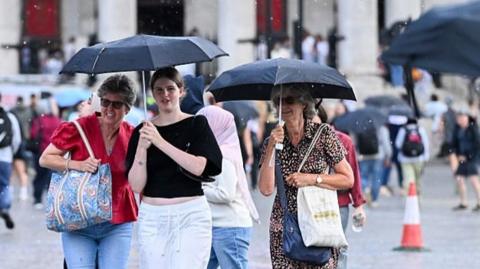 People walk with bags and umbrellas 