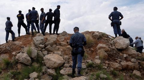 Members of police stand outside the mineshaft where it is estimated that hundreds of illegal miners are believed to be hiding underground in South Africa