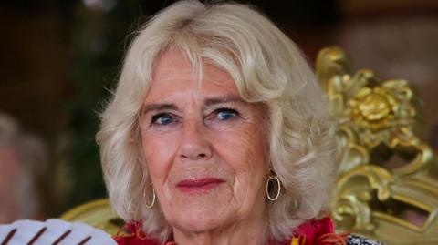 Queen Camilla at the Commonwealth summit in Samoa, she is smiling slightly and has a gold-coloured chair behind her