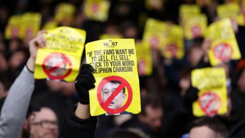 Sheffield Wednesday fans conduct hold up signs in protest against Dejphon Chasniri's ownership of the club
