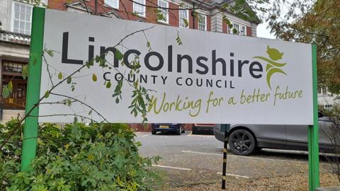 A white and green sign outside County Hall. It reads "Lincolnshire County Council Working for a better future".