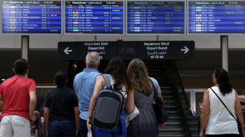 People look at an information board showing some cancelled flights, at the Beirut-Rafic Hariri International Airport, in Beirut, Lebanon August 25, 2024.