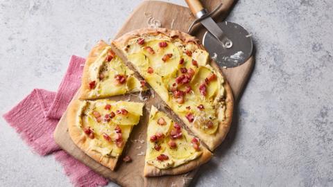 A top-down image shoing a pizza cut into slices on a table.