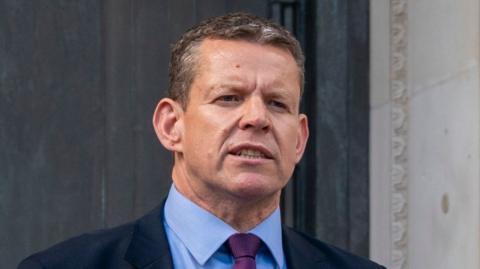 A man, Rhun ap Iorwerth, is in a navy suit.