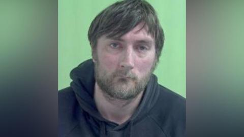 Mugshot of Hall, who has brown hair and a beard.