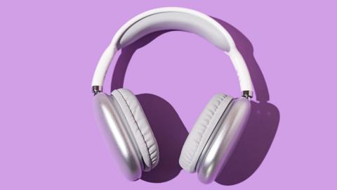 A pair of white headphones on a purple surface